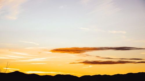 Scenic view of dramatic sky over silhouette mountains during sunset