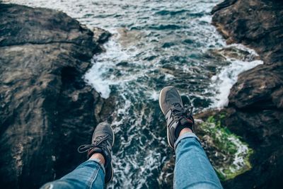 Low section of man standing on rock by sea