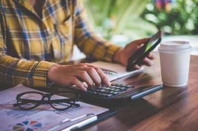 Midsection of man using mobile phone on table