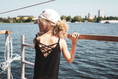 Rear view of girl standing by railing over sea