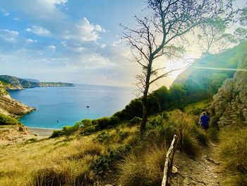 Sunrise on the hidden cove, rear view of people on beach against sky