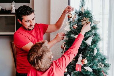 Father and son decorating christmas tree at home