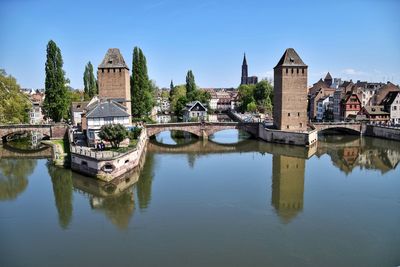 Bridge over river by buildings against sky