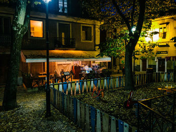 People on illuminated street amidst buildings in city at night
