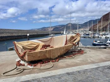 Boats moored at harbor against sky