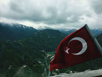 Red flag on mountain against sky,  my village crescent and star on the flag rippling in turkey-