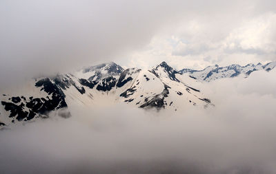 Scenic view of snowcapped mountains against cloudy sky