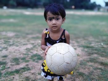 Portrait of girl holding ball on field
