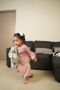 Cute girl standing on sofa at home