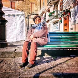 Full length of woman sitting outside building