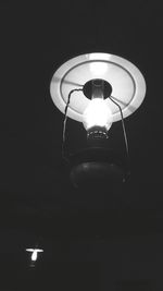 Low angle view of illuminated light bulb against black background