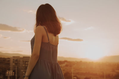 Mature woman standing on terrace against during sunset