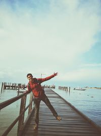 Full length of man standing on pier over sea against sky