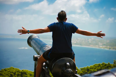 Rear view of man sitting on cannon