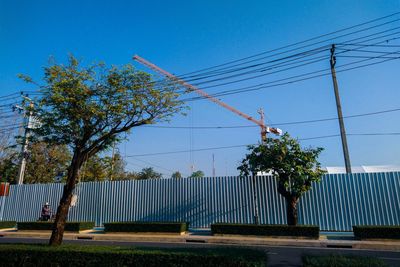 Trees and electricity pylon against sky