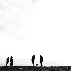 Men standing on beach against sky