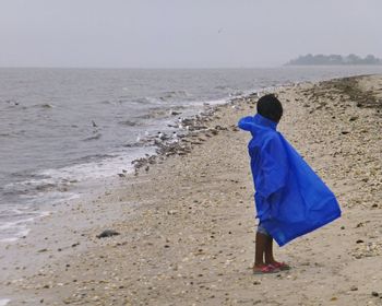 Girl wearing raincoat standing at beach