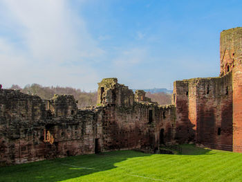 Historical building and grassy field against sky