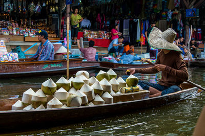 Man selling coconuts in boat at floating market