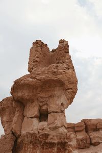 Low angle view of rock formation against cloudy sky