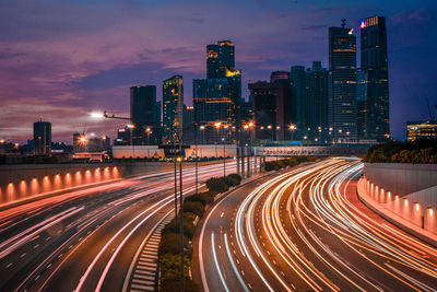 Light trails on road amidst illuminated buildings in city at night