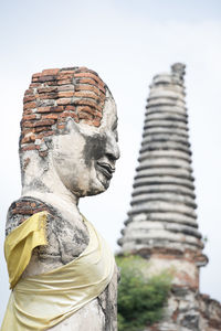 Low angle view of old damaged buddha statue and temple against sky