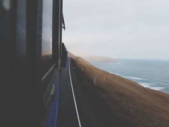 Close-up of road by sea against sky