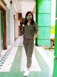 Full length portrait of young woman standing against building