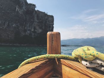 Close-up of rope tied on wood by sea against sky