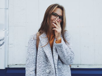 Beautiful young woman standing against wall