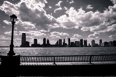 City at waterfront against cloudy sky