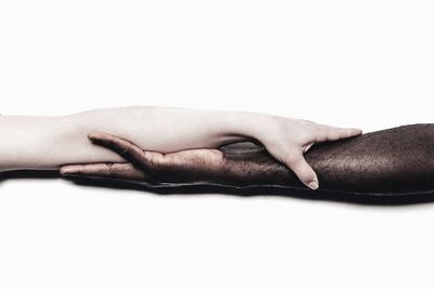 Cropped image of people holding hands against white background