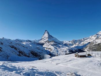 Scenic view of snowcapped mountains against clear blue sky