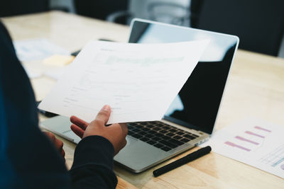 Midsection of man using laptop on table