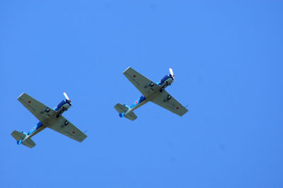 Low angle view of airplane flying against clear blue sky