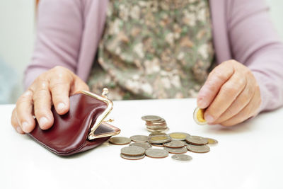 Midsection of man stacking coins on table