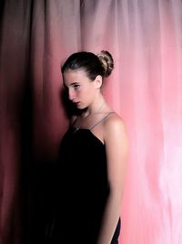 Young woman standing against wall