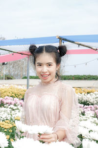 Portrait of smiling young woman standing amidst plants