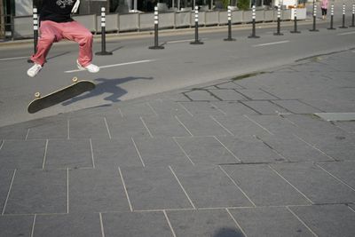 Low section of boy jumping over skateboarding on road