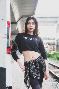 Portrait of beautiful young woman standing against wall