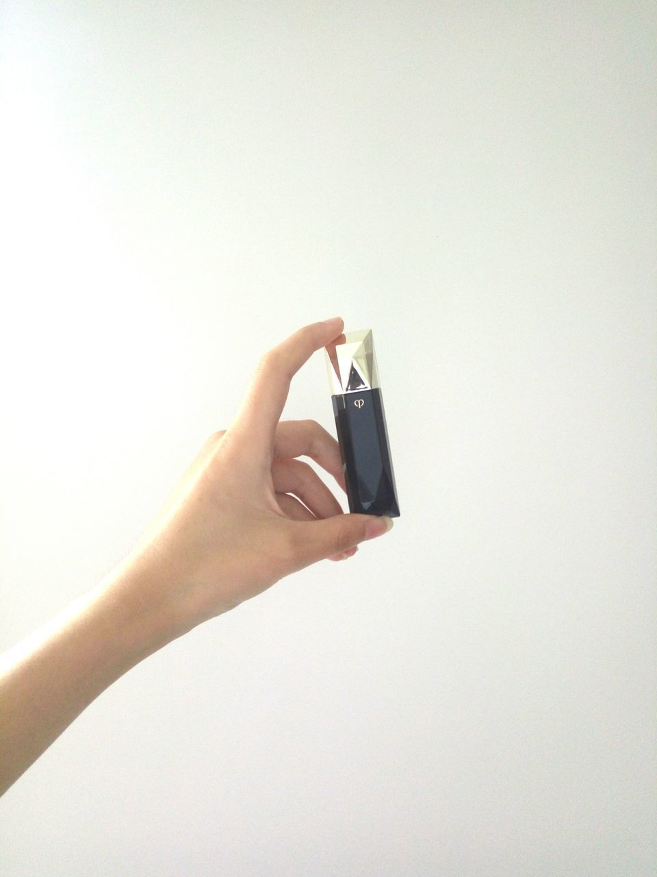 CLOSE-UP OF HAND HOLDING MOBILE PHONE AGAINST WHITE BACKGROUND