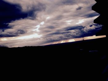 Silhouette of trees against cloudy sky at sunset