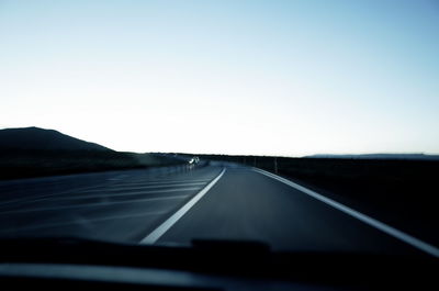 Empty country road against clear blue sky