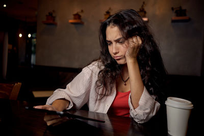 Side view of young woman using mobile phone at home