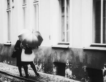 Rear view of woman walking on street against building