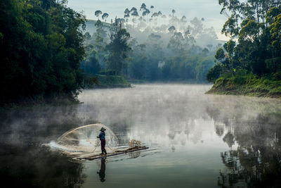 Man in boat on lake against trees