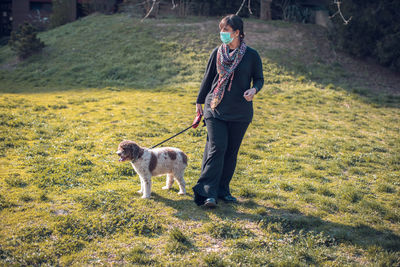 Full length of woman with dog standing on field