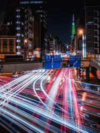 Light trails on city street by buildings at night