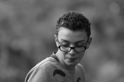 Close-up of teenage boy wearing eyeglasses while looking down outdoors