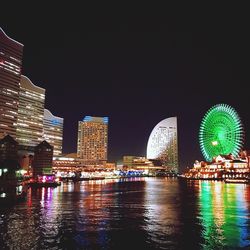 Illuminated city buildings by river at night